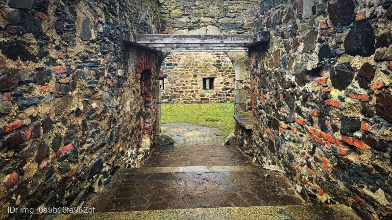 Gepflasterter Durchgang zwischen historischen Steinmauern